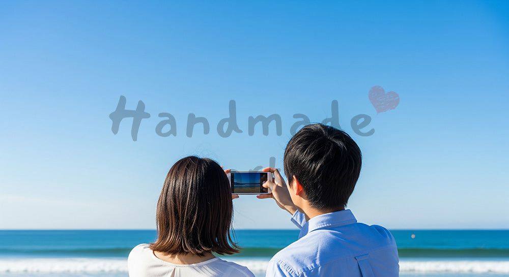 フリー素材 無料 写真|海辺で景色を撮る日本人カップルの後ろ姿、青空と旅のワクワク感の余白