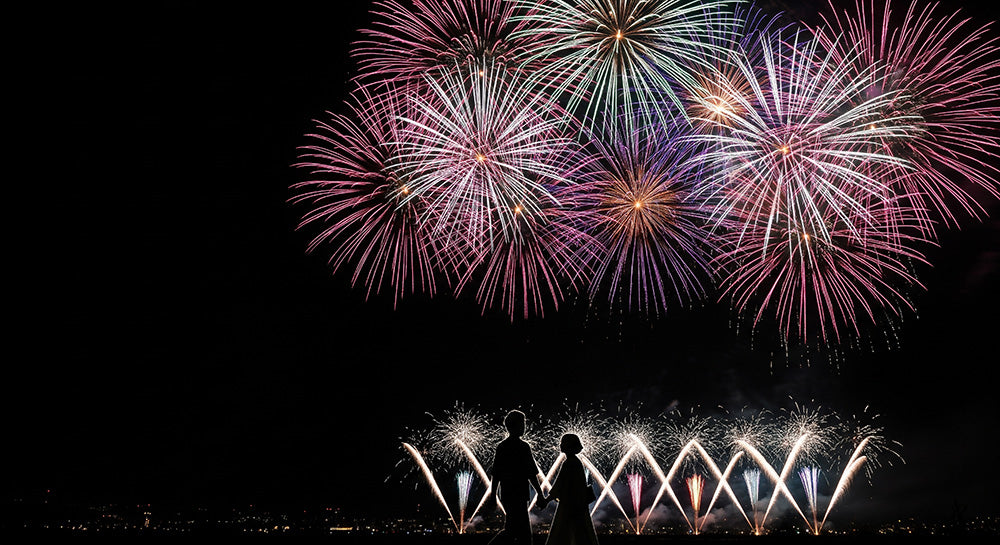 フリー素材 無料 写真|花火の下を歩く日本人カップルシルエット 左側に余白があるロマンチック背景素材 文字入れ向き