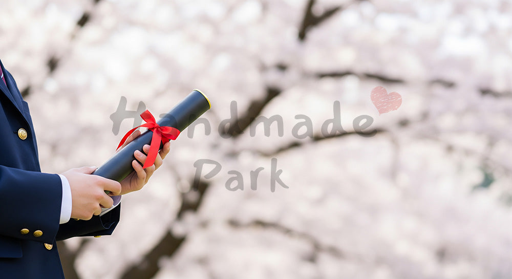 フリー素材 無料 写真|卒業証書筒を持つ日本人の手元 桜ボケ余白|文字入れしやすい余白あり (告知向け)