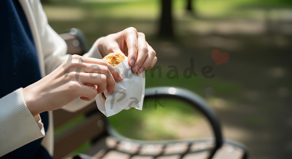 フリー素材 無料 写真｜背景素材公園ベンチで焼き菓子を開封する日本人女性の手元、明るい日中 写真背景