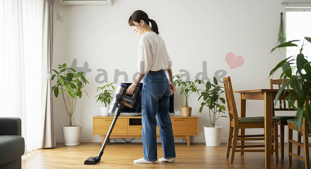 フリー素材 無料 写真｜リビングでコードレス掃除機をかける20代日本人主婦、白壁と木製フロアで清潔感ある日常掃除 背景素材