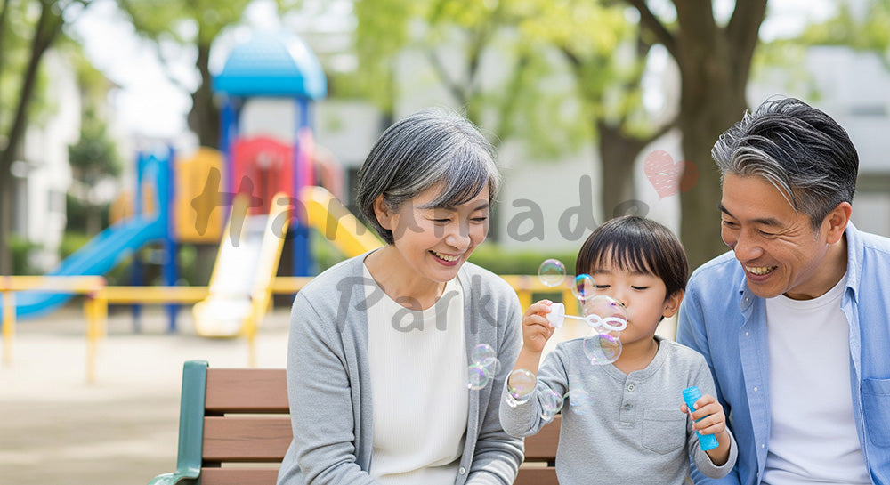 フリー素材 無料 写真｜公園のベンチで孫とシャボン玉遊びを楽しむ日本人祖父母の子育てサポート コピースペースあり
