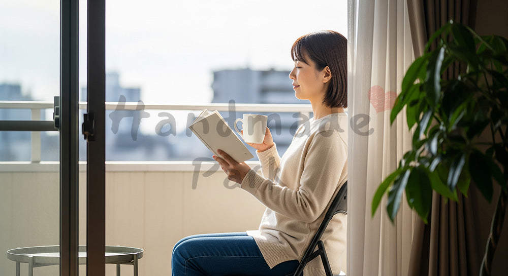 フリー素材 無料 写真｜ベランダで本とマグカップを手に外気浴を楽しむ日本人主婦の休日シーン（表現1）