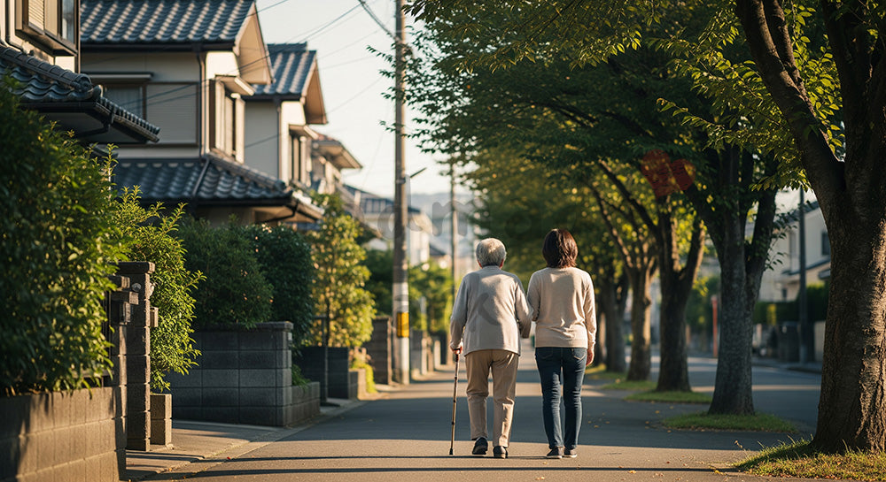 フリー素材 無料 写真｜住宅街の歩道を杖をつきながら娘世代と歩く日本人シニア女性の後ろ姿