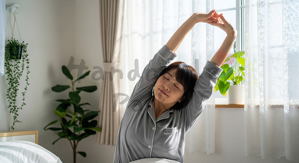 フリー素材 無料 写真｜朝の寝室でストレッチをする日本人女性のセルフケア 余白あり
