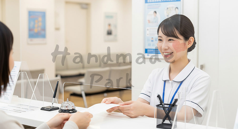 フリー素材 無料 写真｜受付カウンターで患者に受付票を手渡す日本人医療事務スタッフ 写真背景