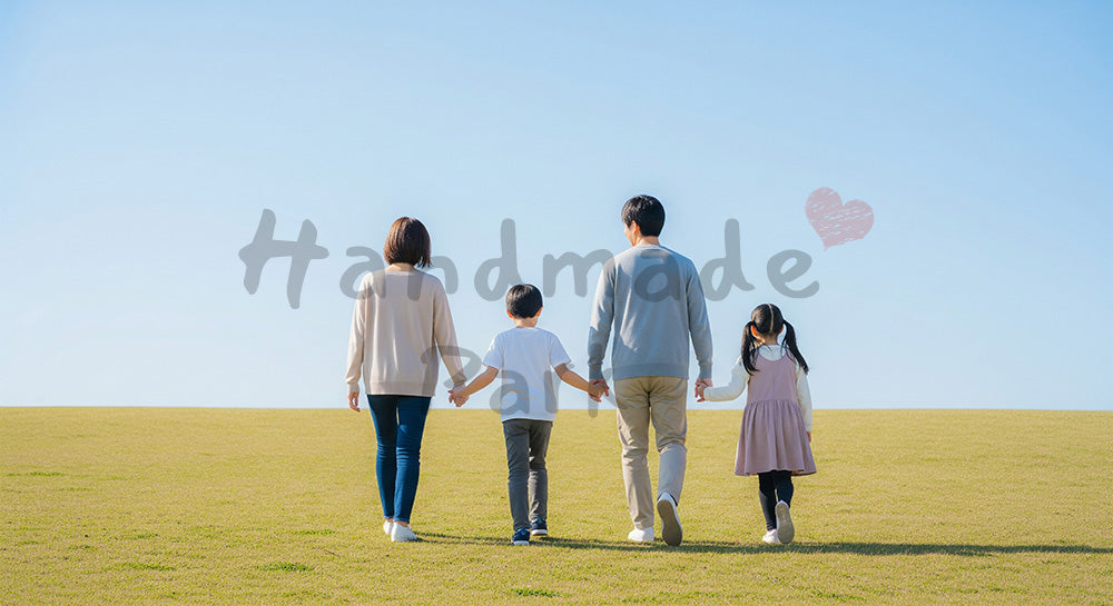 フリー素材 無料 写真｜青い空の丘を歩く日本人家族の後ろ姿、手をつなぐ温かな休日シーン