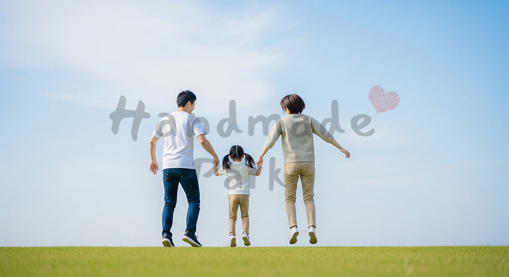 フリー素材 無料 写真｜芝生でジャンプする日本人家族の後ろ姿、青い空と元気な休日のイメージ