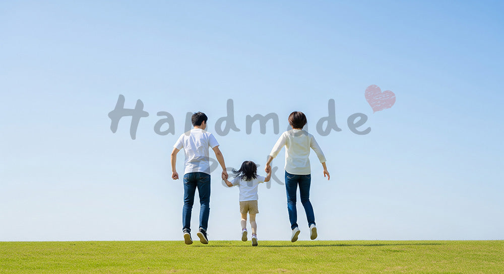 フリー素材 無料 写真｜芝生でジャンプする日本人家族の後ろ姿、青空と元気な休日のイメージ