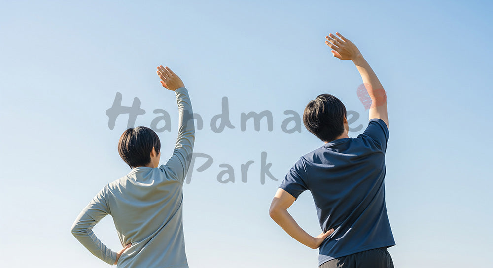 フリー素材 無料 写真｜青い空の下でストレッチする日本人同僚の後ろ姿、健康的な働き方とリフレッシュ