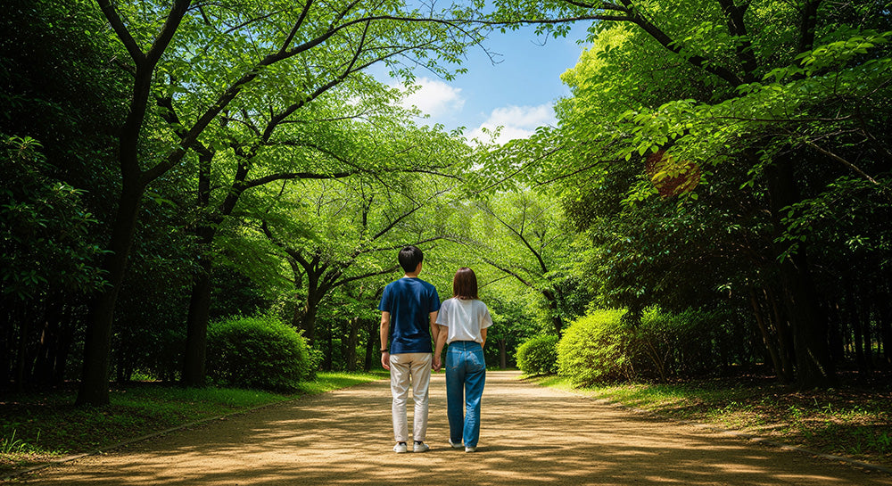 フリー素材 無料 写真｜青空と優しい季節感のデートのある木漏れ日の小道を歩く日本人カップルの後ろ姿