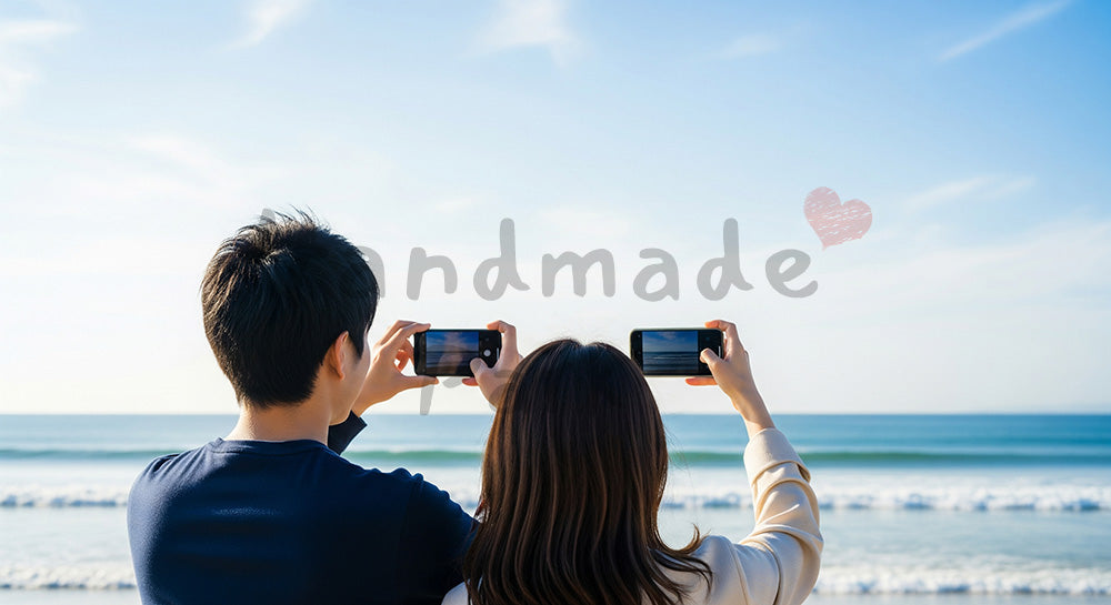 フリー素材 無料 写真｜海辺で景色を撮る日本人カップルの後ろ姿、青空と旅のワクワク感のスペース 背景素材