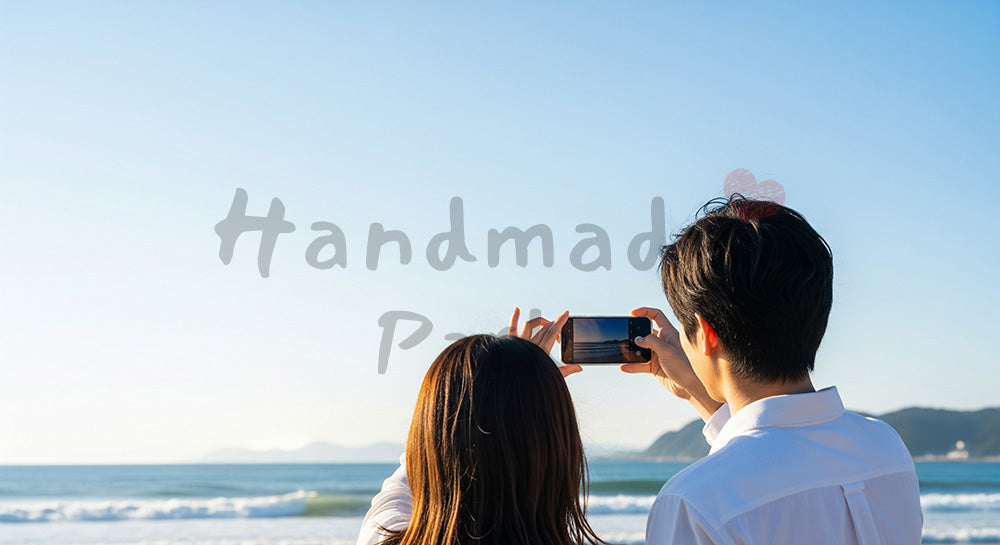 フリー素材 無料 写真｜海辺で景色を撮る日本人カップルの後ろ姿、青空と旅のワクワク感の空きスペース