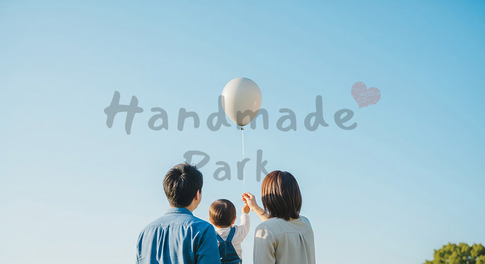 フリー素材 無料 写真｜風船を見上げる日本人家族の後ろ姿、青い空と子どもの喜びが伝わる公園