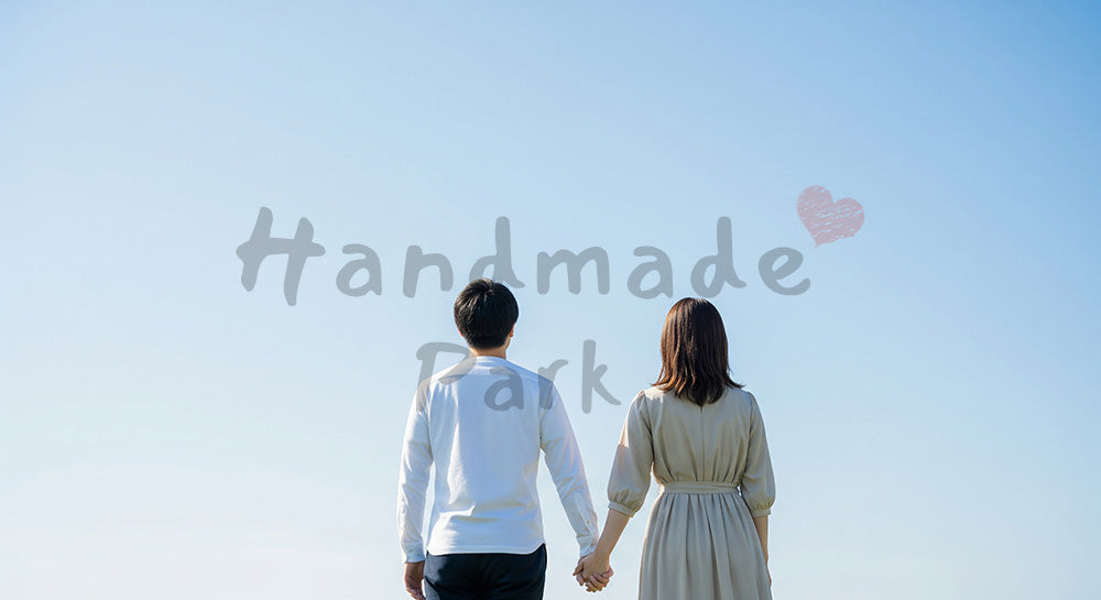 フリー素材 無料 写真｜希望を感じる温かな余白背景のある青空を見上げて手をつなぐ日本人カップルの後ろ姿