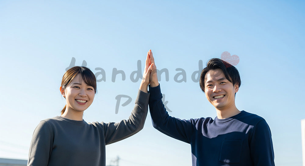フリー素材 無料 写真｜青い空の下でハイタッチする日本人同僚（正面）