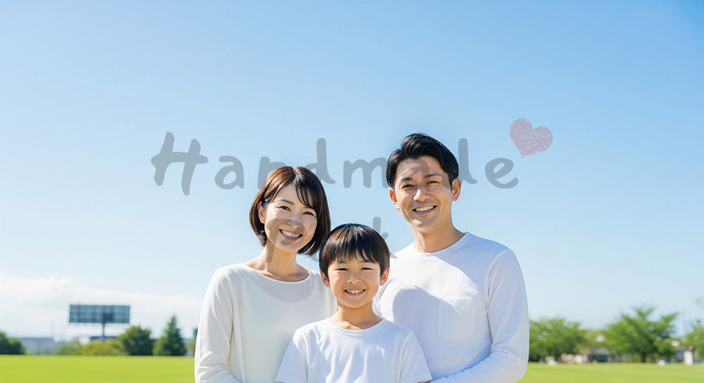 フリー素材 無料 写真｜青い空と芝生で笑う日本人家族（正面・集合）