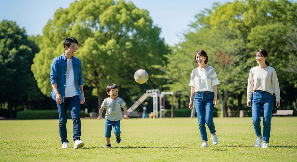 フリー素材 無料 写真｜日差しのある公園の芝生でボール遊びをする日本人家族、元気で爽やかな休日写真