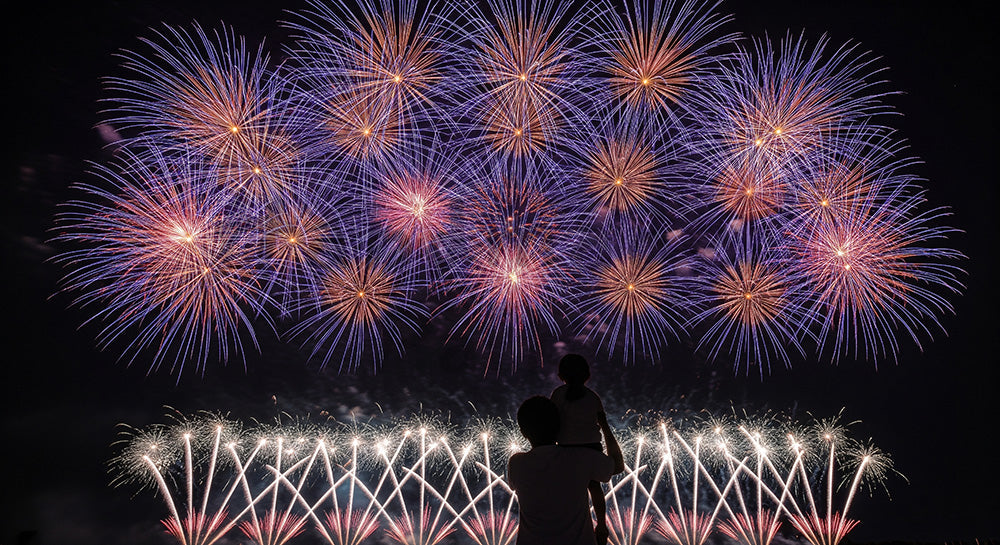 フリー素材 無料 写真｜花火と肩車の日本人親子シルエット 夜空の余白が大きい温かい夏の背景 文字入れ向き