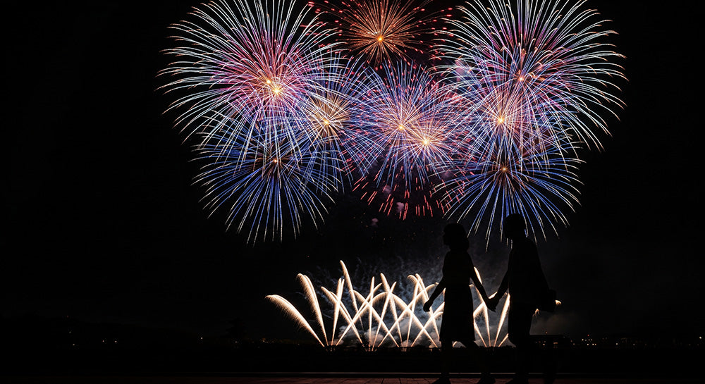 フリー素材 無料 写真｜花火の下を歩く日本人カップルシルエット 左側に余白があるロマンチック背景素材