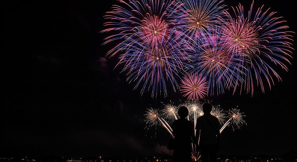 フリー素材 無料 写真｜左側に余白があるロマンチック背景素材、花火の下を歩く日本人カップルシルエットが活きる